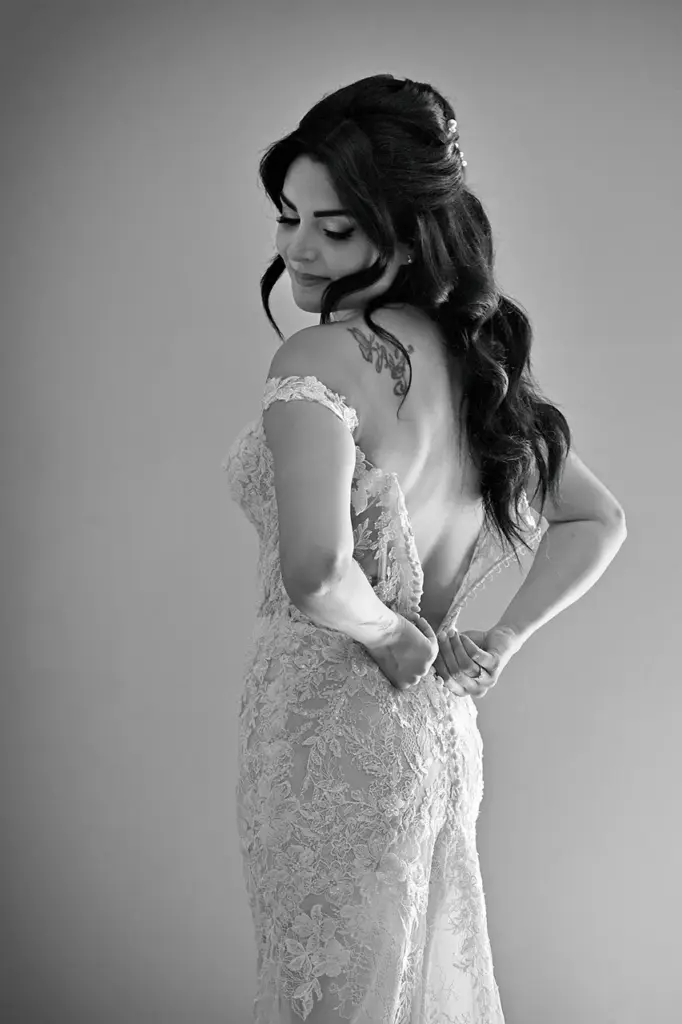 Sposa mentre chiude l'abito da sposa durante i preparativi del matrimonio.