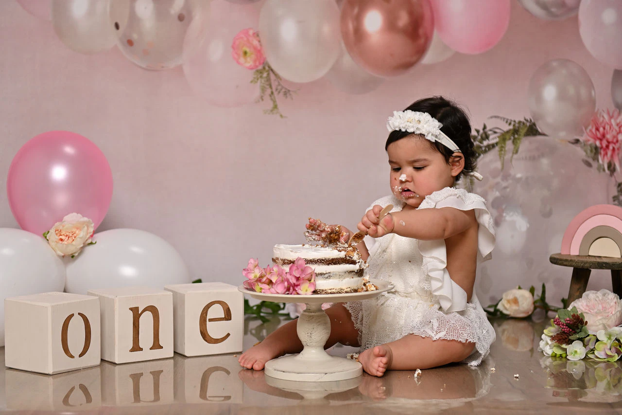 Bambina con torta e palloncini rosa durante il servizio fotografico Smash Cake