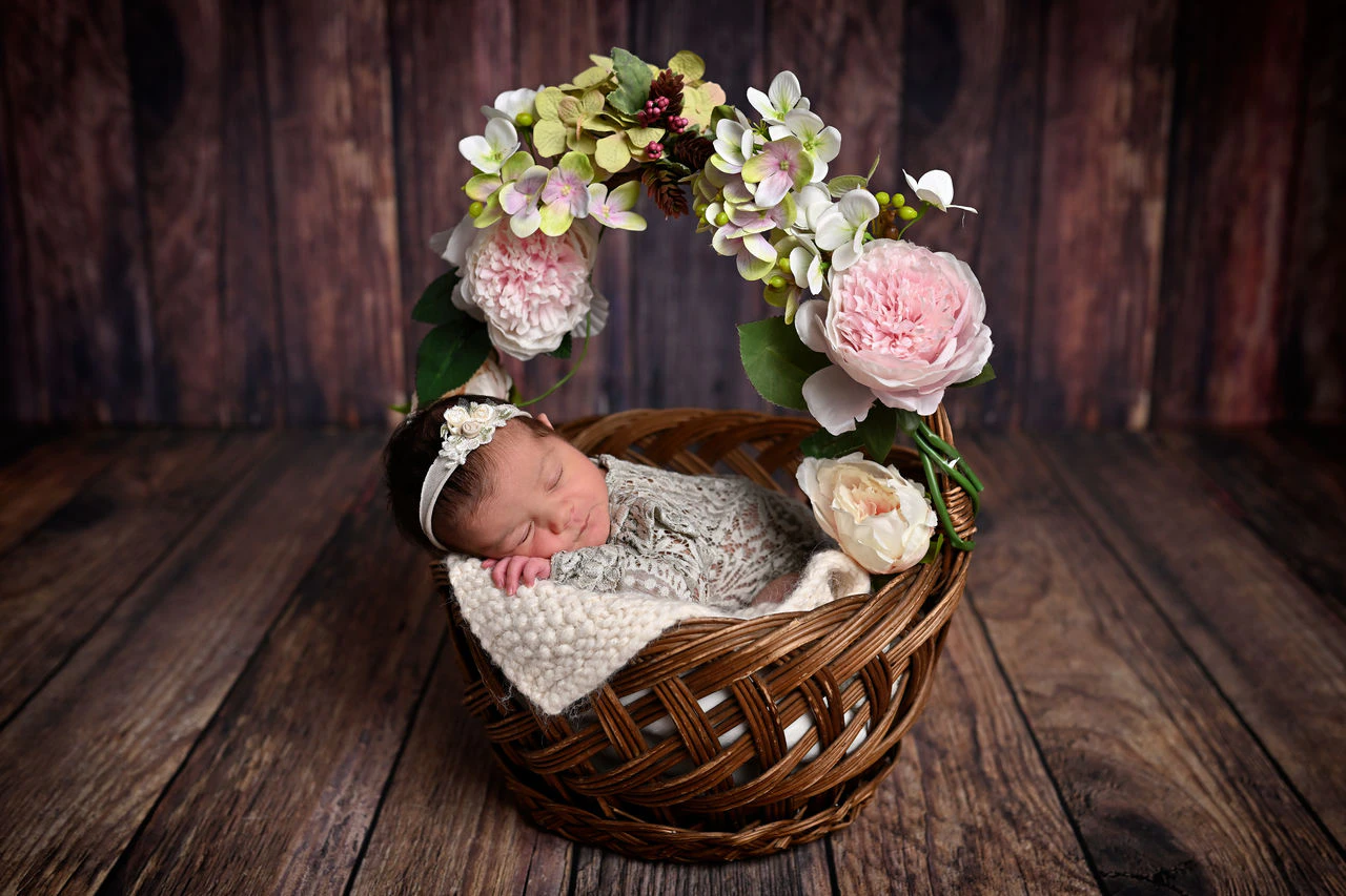 Neonato addormentato in un cestino decorato con fiori