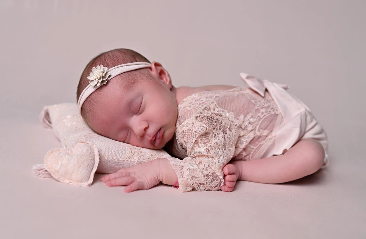 Neonata addormentata su sfondo rosa durante il servizio fotografico newborn