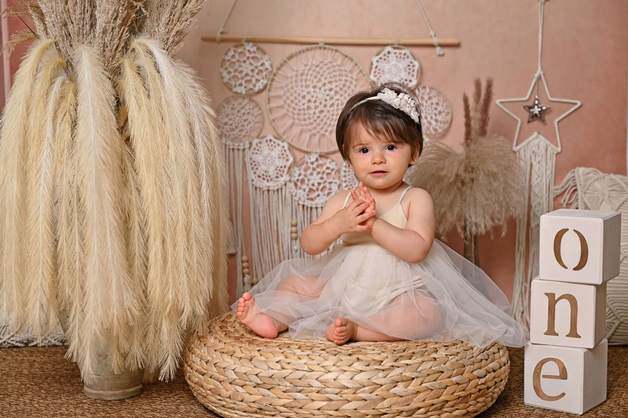 Bambina seduta nella scenografia boho durante il servizio fotografico del primo compleanno