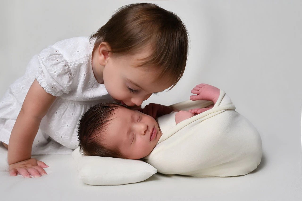 Bambina insieme al fratellino neonato durante un servizio fotografico newborn