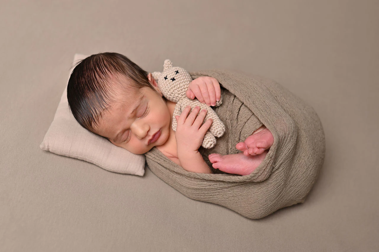 Neonato addormentato in posa su morbido tessuto beige