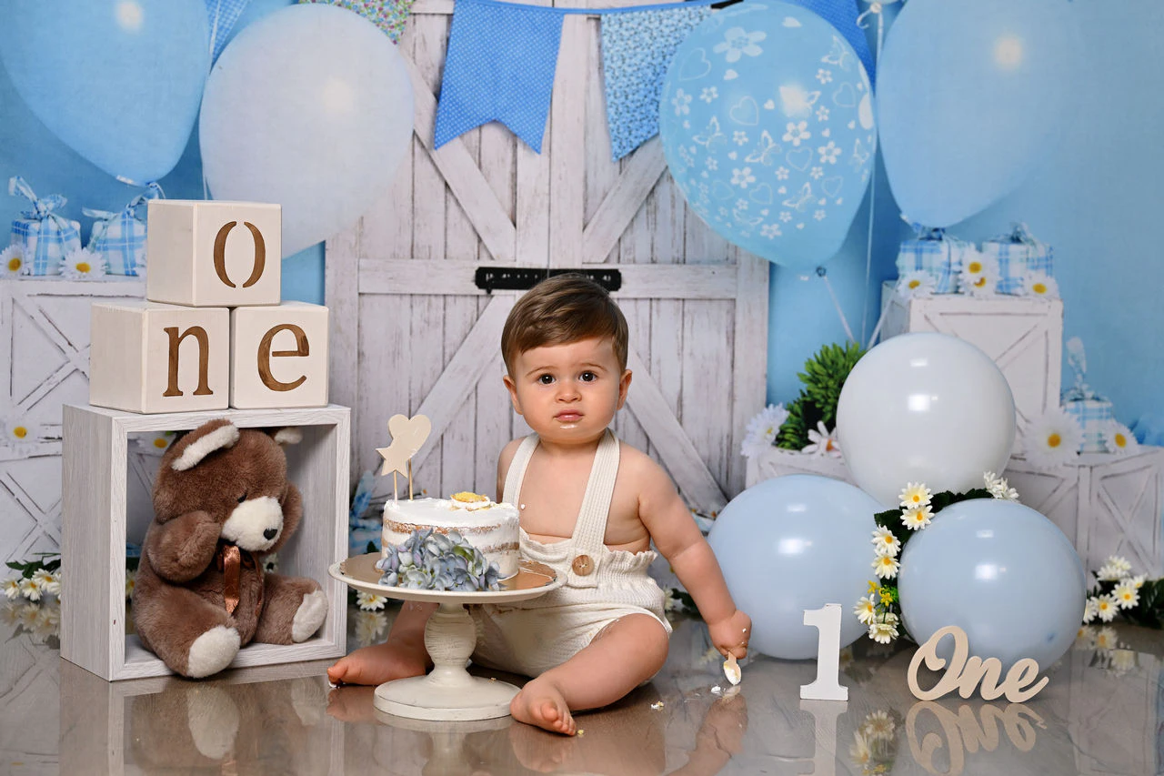 Bambino nella scenografia azzurra con palloncini per il primo compleanno