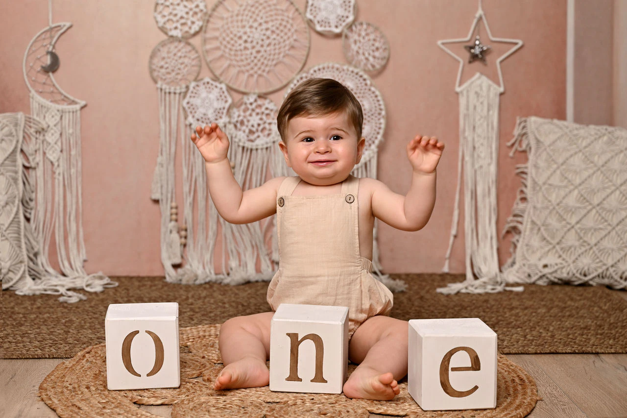 Bambino seduto accanto ai cubi ONE durante il servizio del primo compleanno