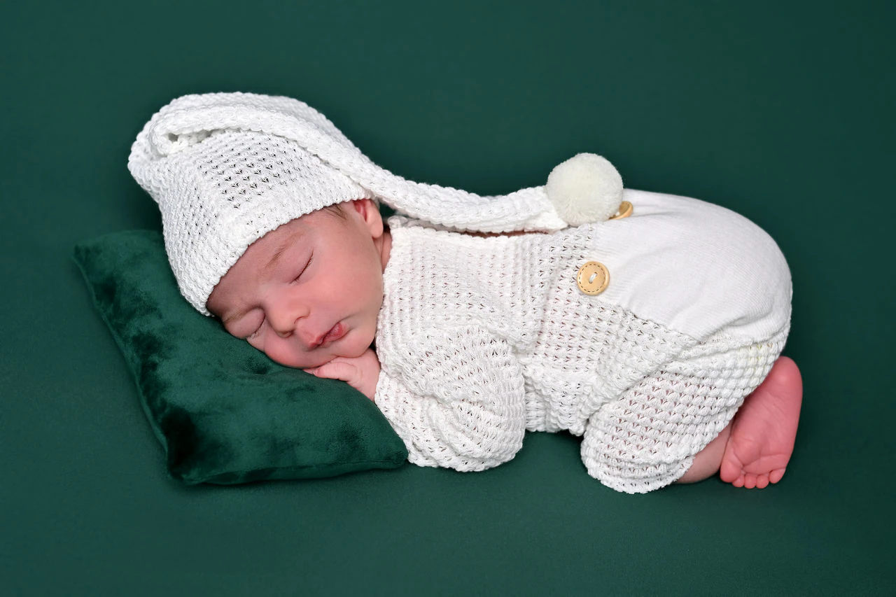 Neonato addormentato avvolto in una coperta verde