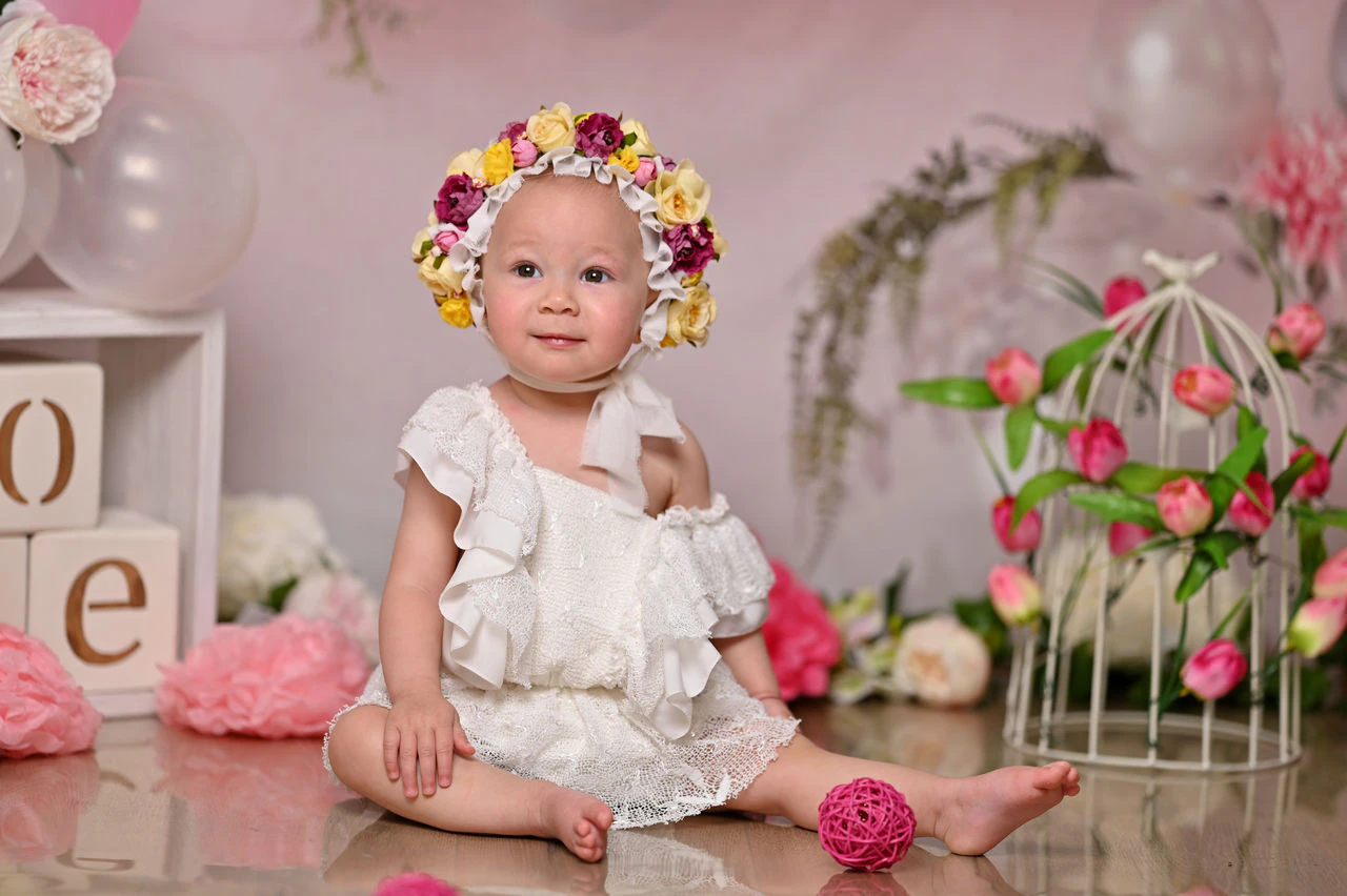 Bambina con corona di fiori nella scenografia del primo compleanno