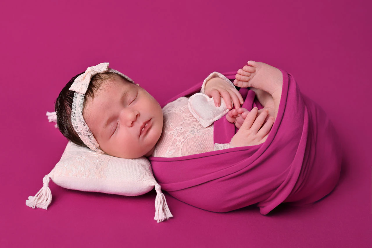 Neonata addormentata avvolta in un tessuto fucsia