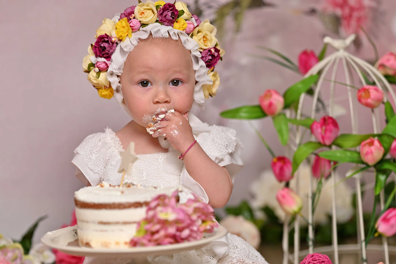 Bambina con corona di fiori mentre assaggia la torta Smash Cake