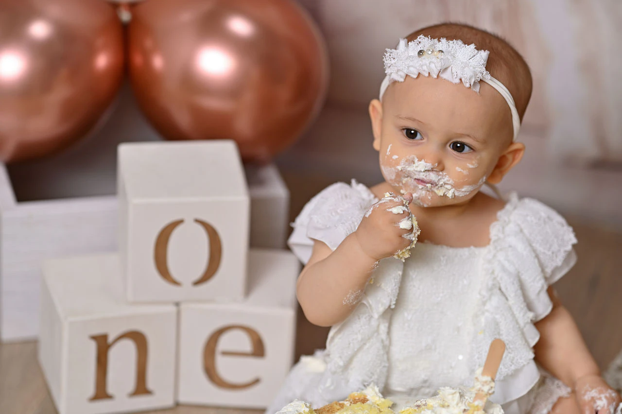 Bambina mentre assaggia la torta durante il servizio fotografico del primo compleanno