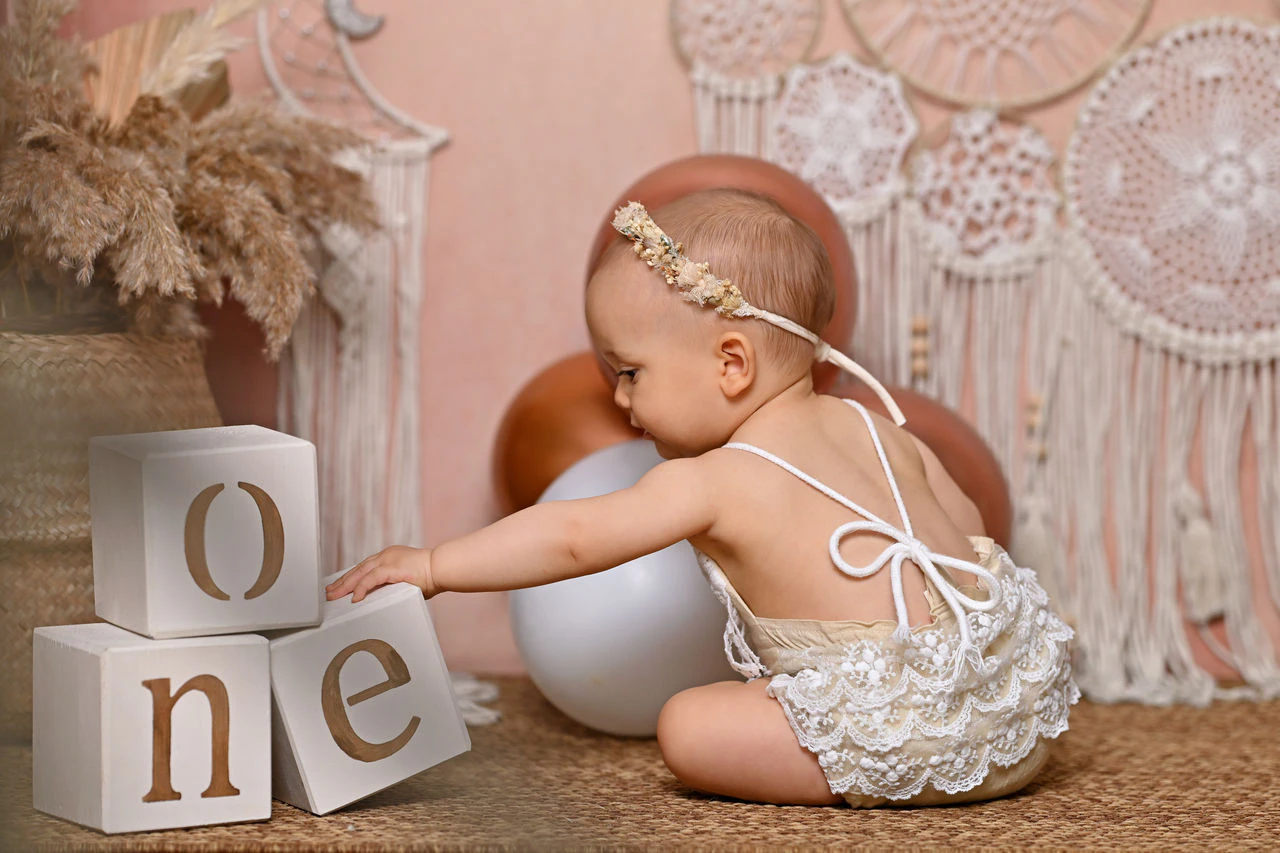 Bambina seduta accanto ai cubi ONE nella scenografia del primo compleanno