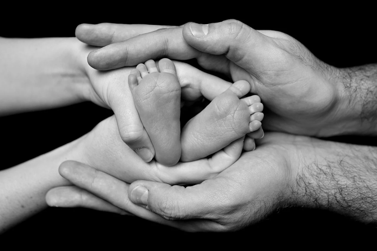 Mani dei genitori che avvolgono delicatamente quelle del neonato
