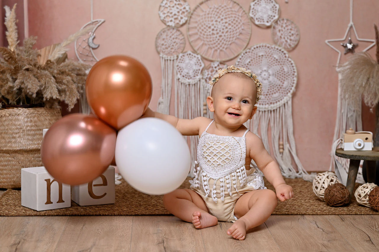 Bambina sorridente tra i palloncini durante il servizio fotografico del primo compleanno