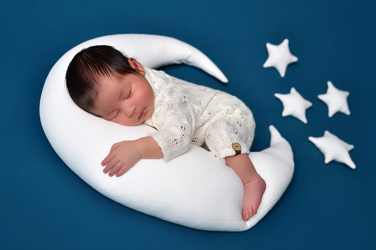 Neonato addormentato su una luna con stelle durante il servizio newborn
