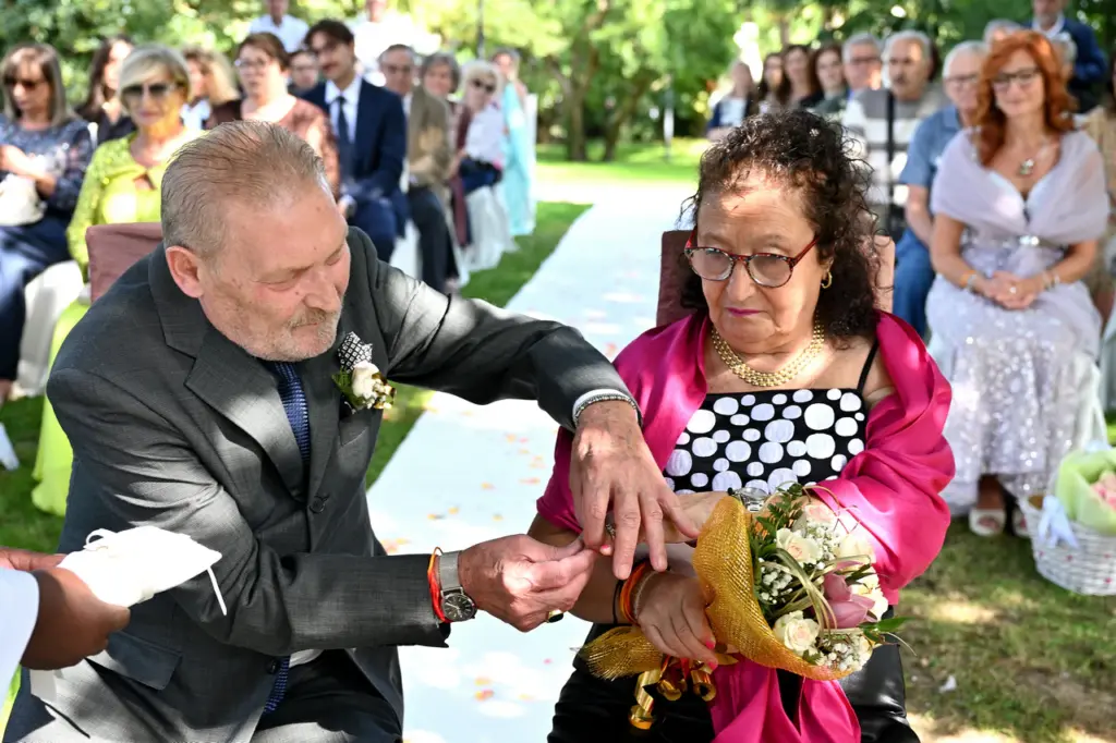 Salvatore e Maria si scambiano le fedi durante la cerimonia delle nozze d'oro nel giardino.