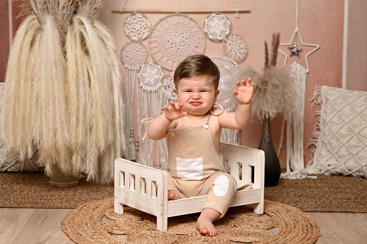 Bambino seduto su una piccola culla nella scenografia del primo compleanno