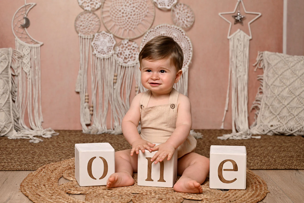Bambino seduto con i cubi ONE durante il servizio fotografico del primo compleanno