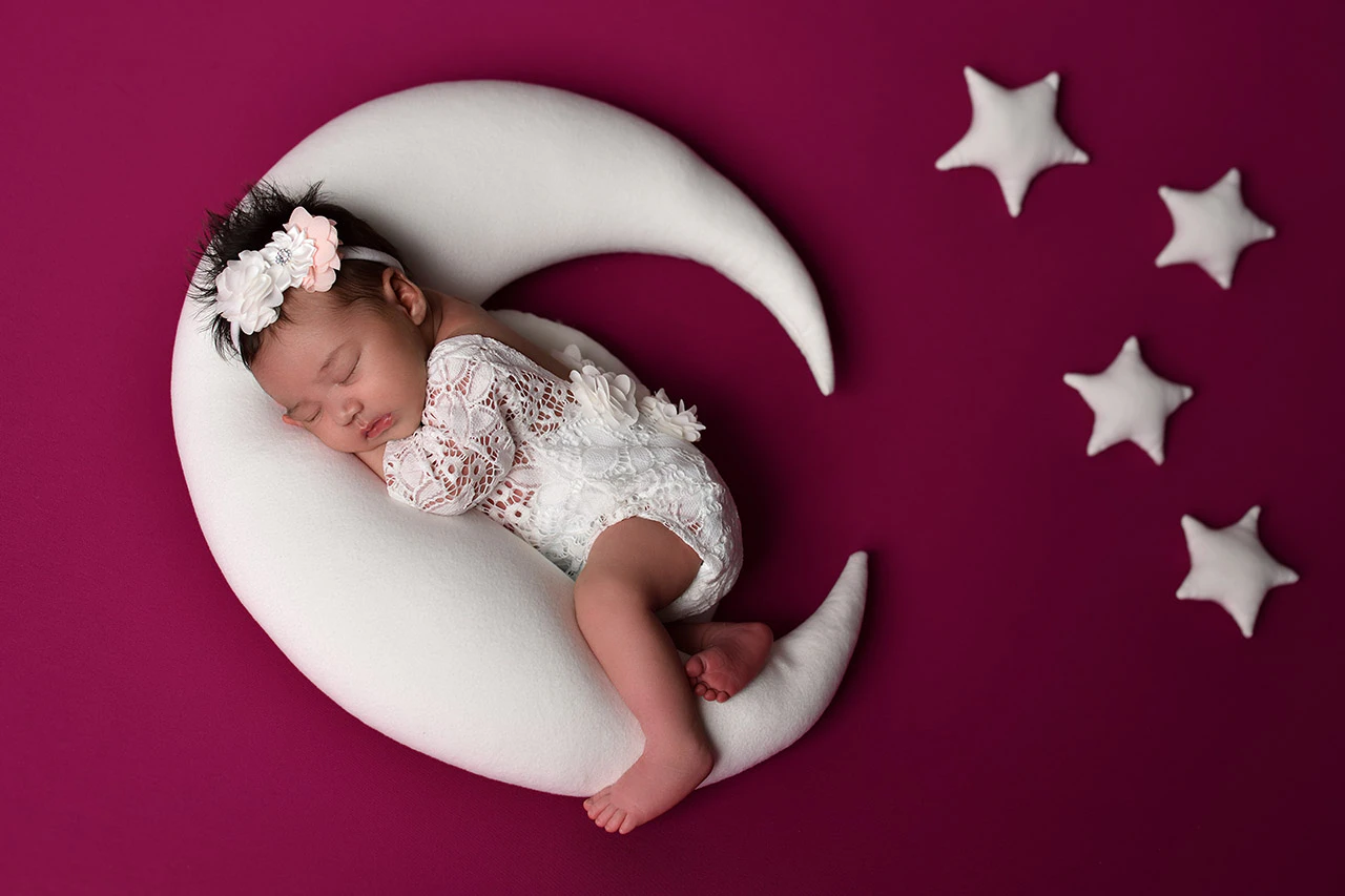 Neonato addormentato su una luna con stelle decorative