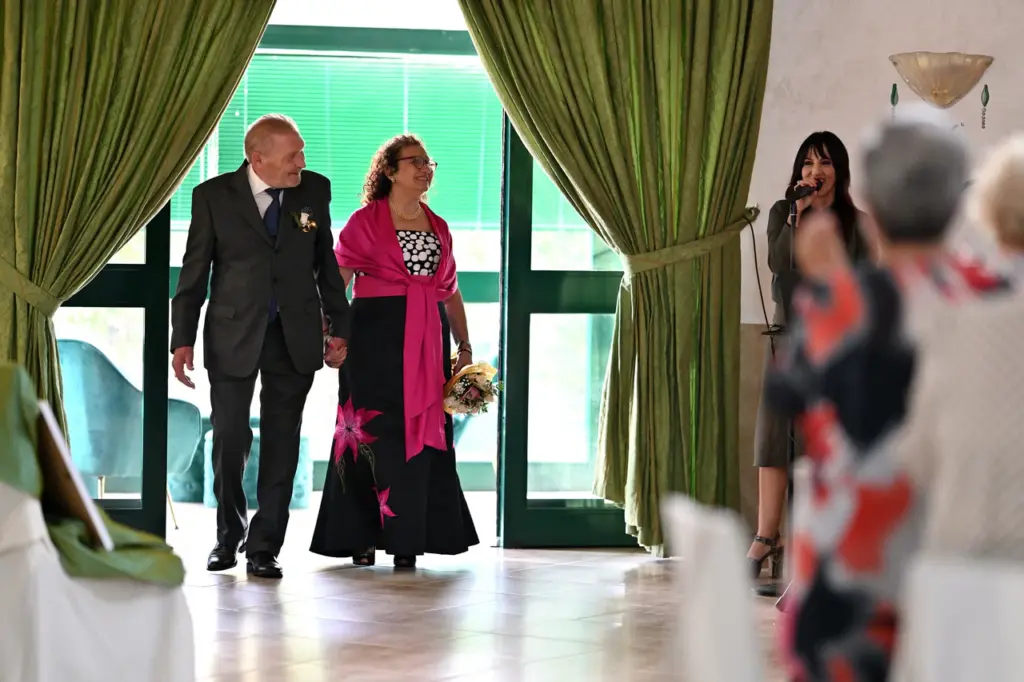 Salvatore e Maria entrano sorridenti nella sala del ricevimento della Reggia di Torrazza Piemonte, accolti dagli invitati.